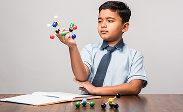male student holding science model of atoms